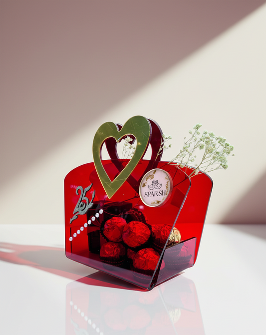 Red decorative box with flowers and a heart-shaped design on a reflective surface.