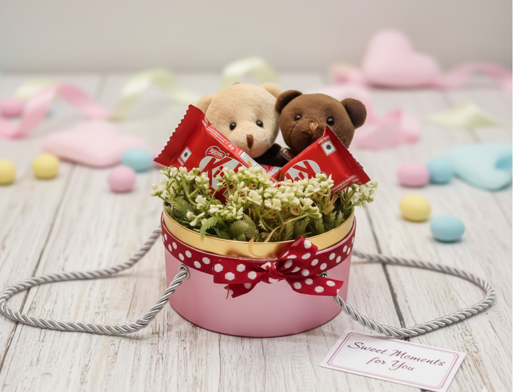 Two teddy bears with a small potted plant on a wooden surface with colorful blurred items in the background.