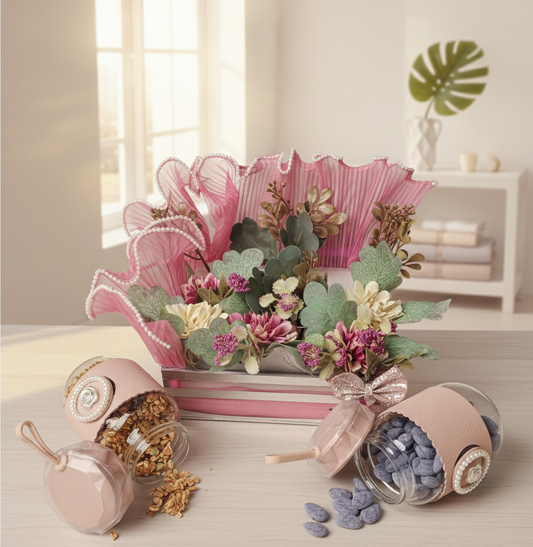 Decorative arrangement with pink vase, flowers, and small jars on a light surface.