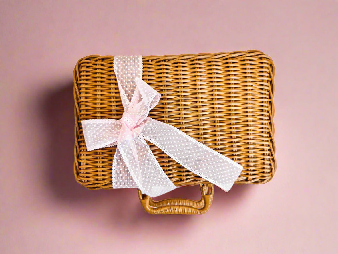 Wicker basket with a pink polka dot ribbon on a white background
