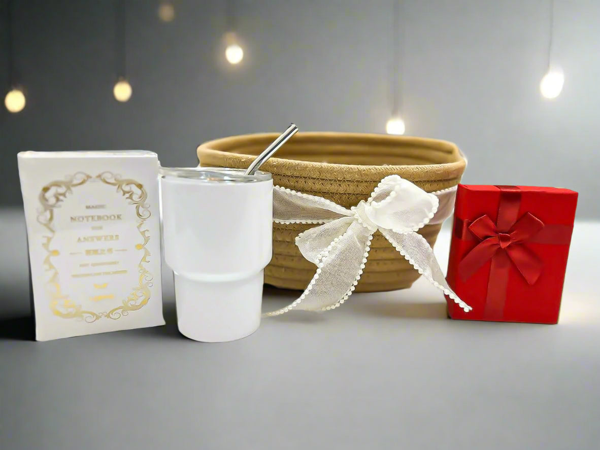 White tumbler with straw, notebook, woven basket, and red gift box on a white surface.