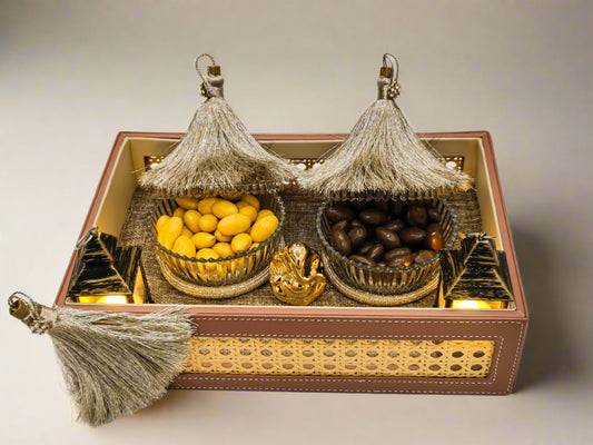 Decorative tray with bowls of fruits and a small statue on a white background