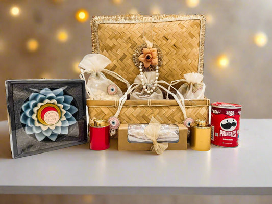 Decorative gift basket with candles, a can of Pringles, and a framed item on a table.