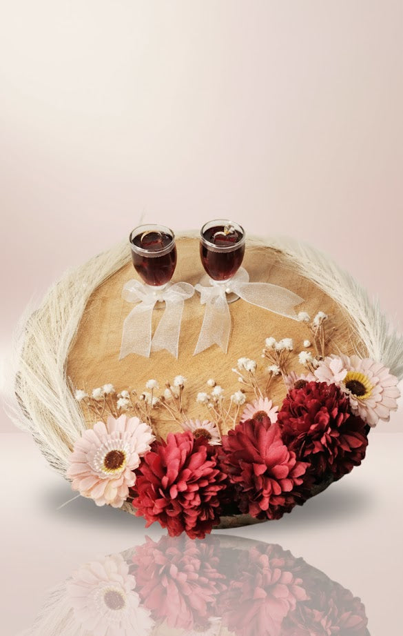 Decorative wreath with flowers and two small glasses on a white background